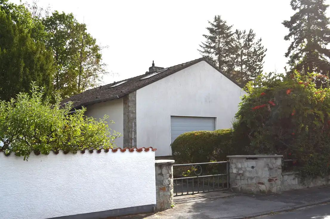 Weißes Einfamilienhaus mit Garten und geschlossenem Metalltor