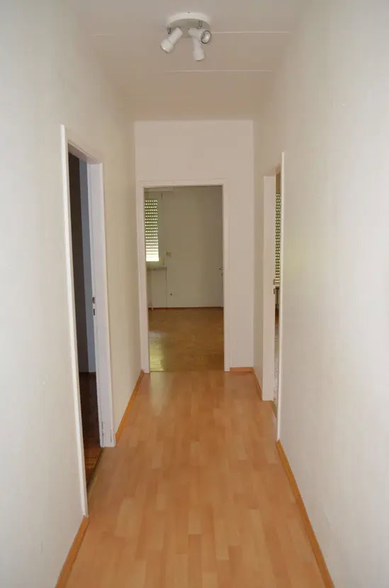 Leerer Flur mit Holzboden und weißen Wänden.