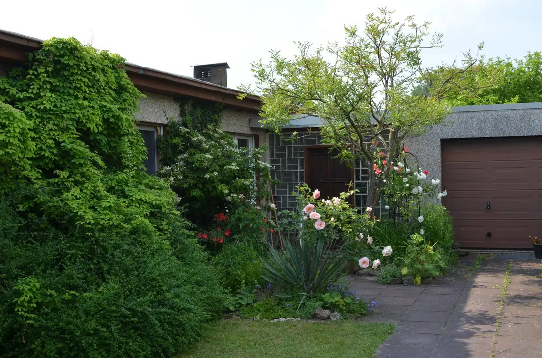 Blühender Garten vor einem Haus mit Garage.