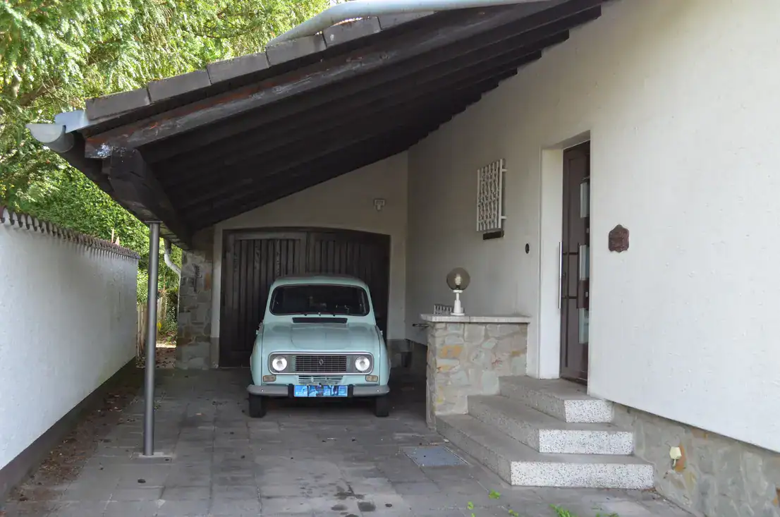 Hellblauer Oldtimer unter Carport vor Hausgarage