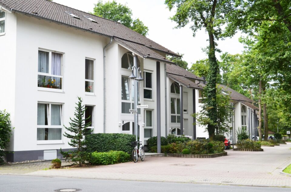 Moderne weiße Reihenhäuser mit Bäumen und Fahrrad.