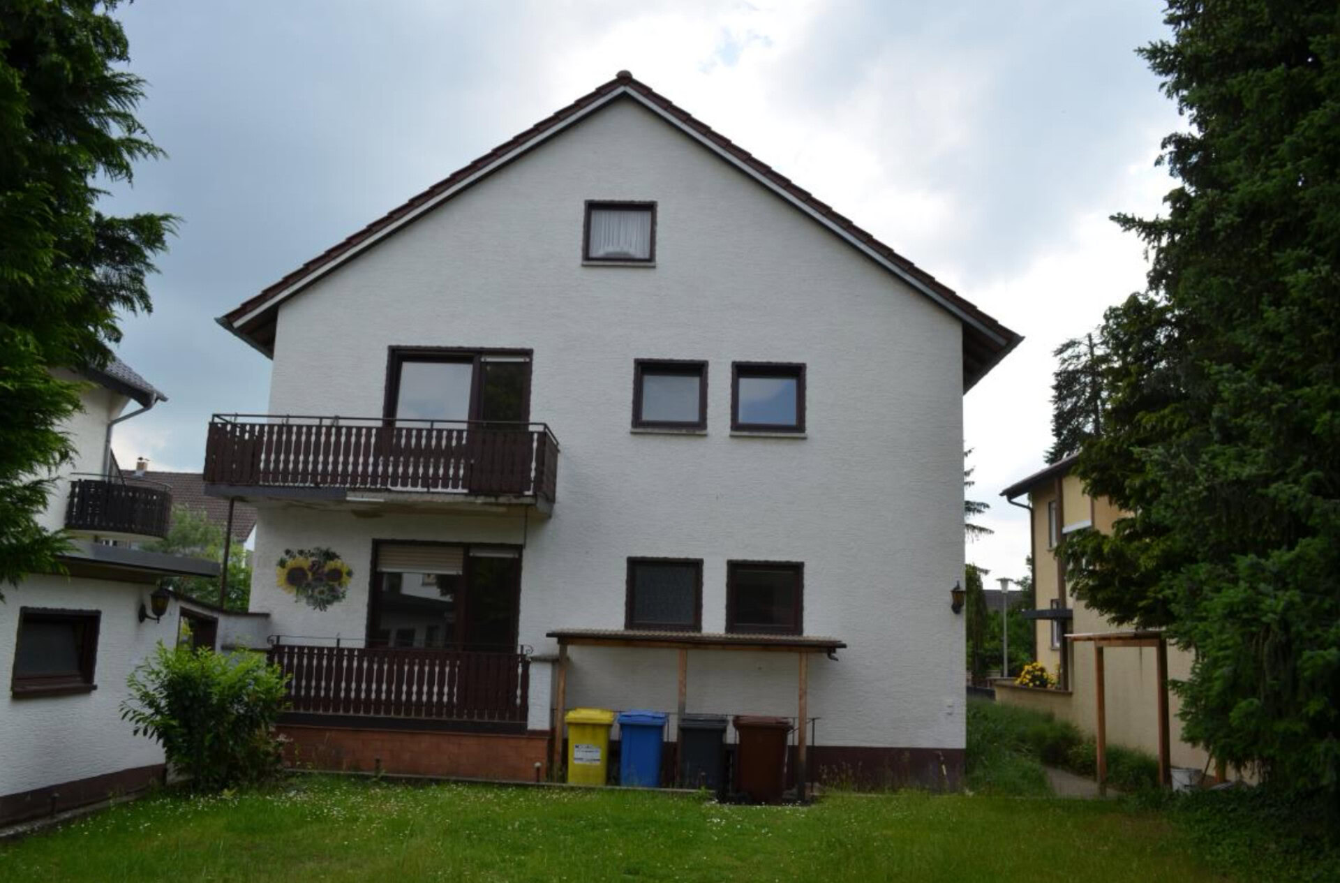 Zweistöckiges Haus mit Balkonen und Mülltonnen