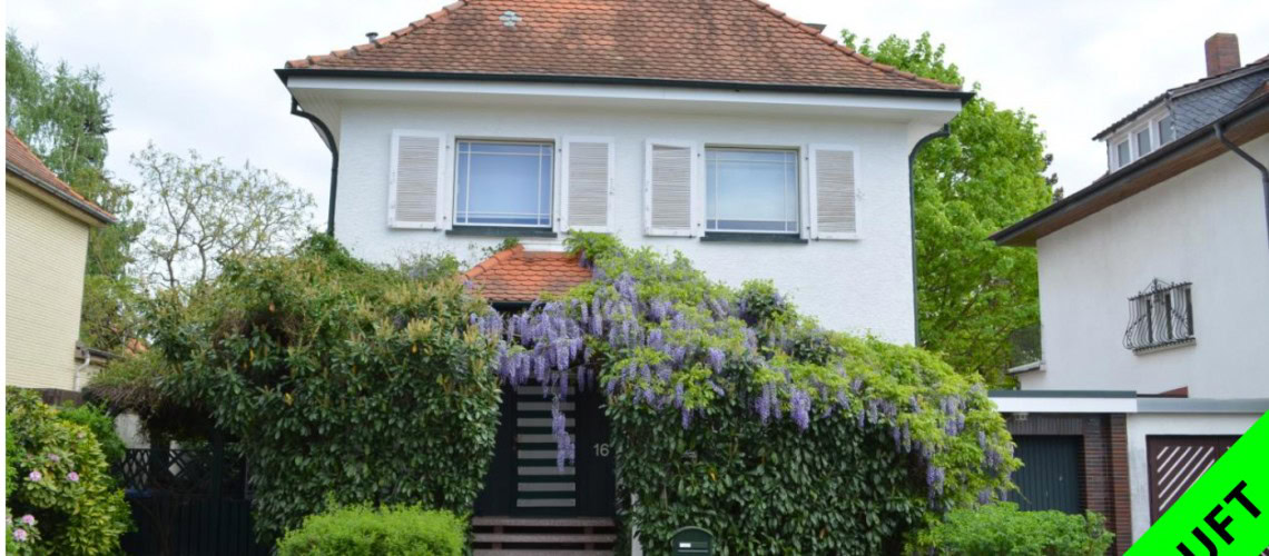 Zweistöckiges Haus mit blühender Kletterpflanze