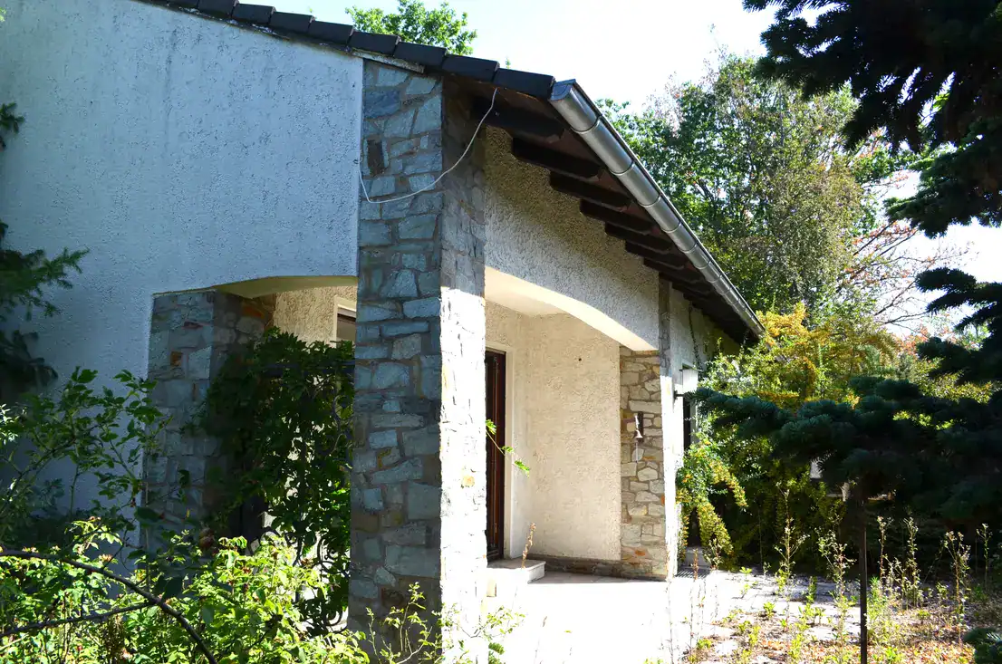 Hausveranda mit Natursteinpfeilern und üppigem Garten