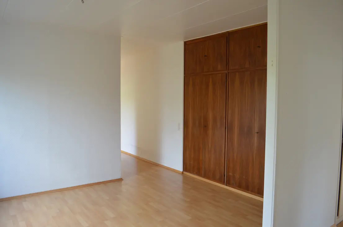 Leeres Zimmer mit Parkettboden und Wandschrank