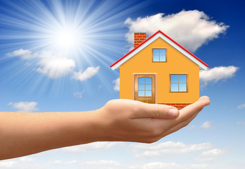 Haus auf einer Hand unter blauem Himmel