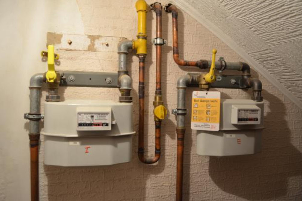 Zwei Gaszähler mit gelben Absperrventilen im Keller.