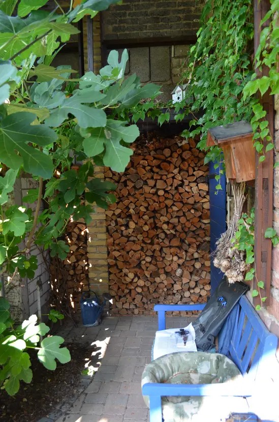 Holzstapel hinter Gartenbank im Hof
