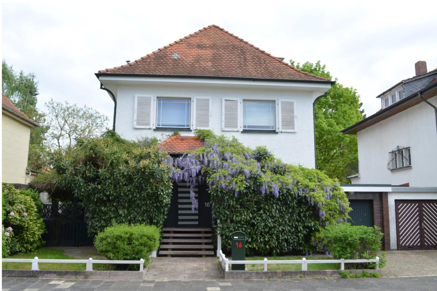 Haus mit blühendem Strauch im Garten